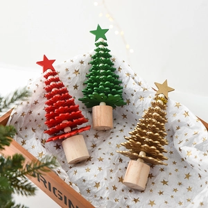Miniature wooden Christmas tree set with red, green and gold layers on festive gift box