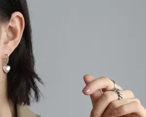 Model wearing retro style twisted rope rings and heart pearl earrings in silver finish