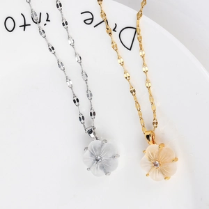 Elegant stainless steel flower pendant necklaces in gold and silver finishes on a tray