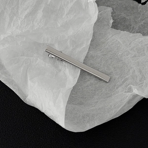 Detailed view of a polished silver metal alligator hair clip on a minimalist textured surface