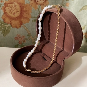 Détail d'un collier de perles baroques d'eau douce avec chaîne torsadée dorée en coffret