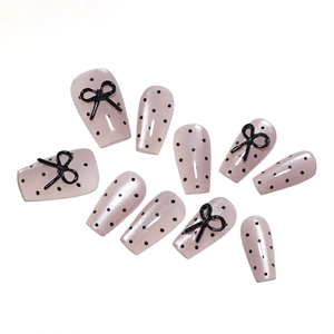 Pink press-on nails with black polka dots and 3D bow charms in long trapezoid shape