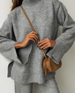 Detail of high turtleneck sweater with side slits and vintage brown leather crossbody bag
