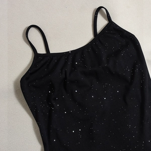 Close-up of black ribbed knit camisole with sparkling silver sequins on textured fabric