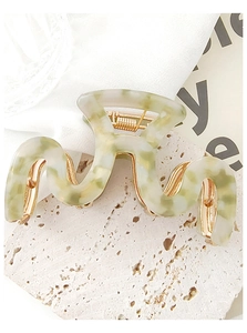 Detail of snake-shaped acetate hair claw clip with green marble texture and gold spring
