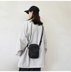 Detail view of black nylon crossbody phone bag with adjustable strap and snap buckle
