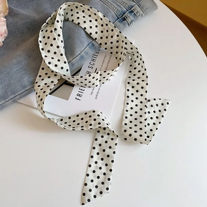 Close-up of a white satin silk scarf with black polka dots on denim background