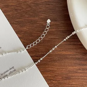 Close-up of S925 sterling silver beaded anklet with heart pendant on wooden surface
