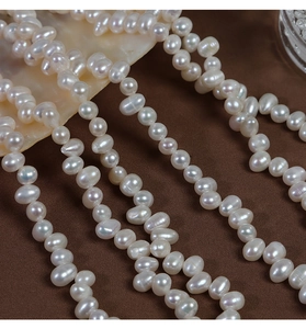 Macro detail of irregular creamy white natural freshwater pearls on textured brown fabric