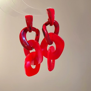 Detail of red acrylic chain link drop earrings with dark marble texture and silver needles