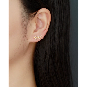 Close-up of a gold leaf-shaped earring with small diamonds worn on a model's ear