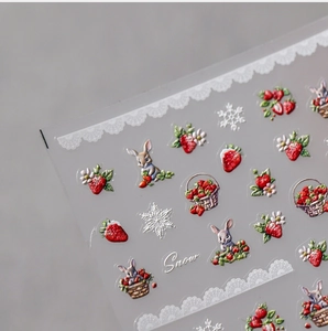 Macro view of 3D embossed strawberry and bunny nail art stickers with Snow text detail