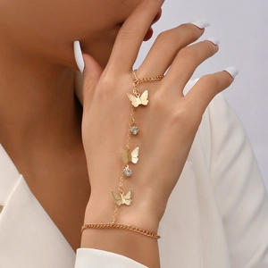 Detail of gold butterfly finger bracelet with rhinestones worn on a model's hand