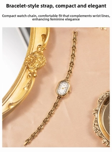 Detail of elegant gold bracelet watch with oval dial on champagne silk fabric background