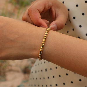 Close-up of elegant gold cube beaded bracelet worn on wrist with minimalist modern style