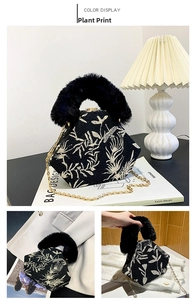 Detail of black fabric hexagonal bag with floral embroidery and gold chain strap
