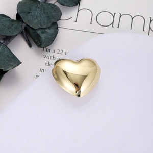 Ciondolo a cuore dorato lucido su supporto bianco con elegante sfondo di eucalipto