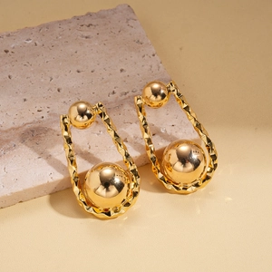 Detalle macro de pendientes en U bañados en oro de 18K con textura martillada sobre piedra