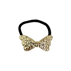 Macro detail of golden hammered bow hair tie with high-elasticity black braided band