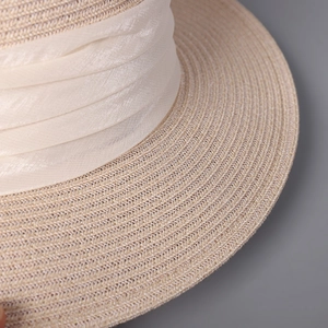 Détail du chapeau en paille tressée avec un ruban plissé en satin crème élégant