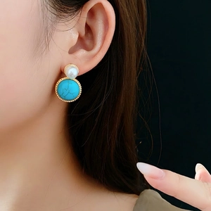 Vintage style round pearl and turquoise earrings with golden beaded edges on model