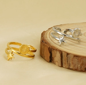 Detail of 18K gold and silver star rings displayed on a rustic wood and textured base