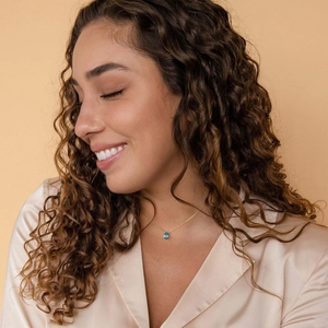 Fashionable gold chain necklace with a blue teardrop gemstone pendant worn by a model