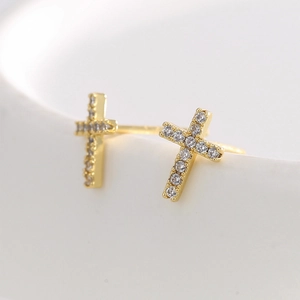 Elegant gold cross stud earrings featuring brilliant zircon inlay on a ceramic display