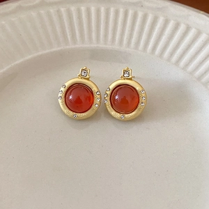 Macro detail of vintage gold stud earrings with carnelian stone and small crystals