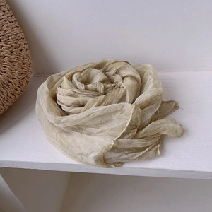 Detail of khaki pleated vintage silk scarf showing soft wrinkled texture and light fabric