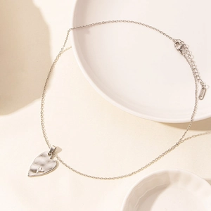 Macro shot of double heart pendant with hammered texture on gold stainless steel chain