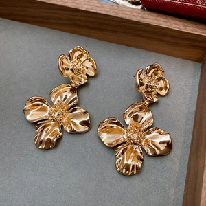Dettaglio macro di orecchini a fiore vintage dorati con petali a doppio strato testurizzati