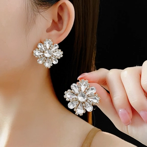 Detail of silver flower earrings with sparkling rhinestones worn on ear lobe