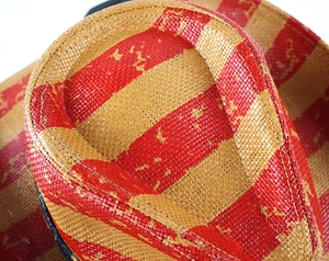Top macro view of woven straw hat featuring bold red and beige stripes with fine texture