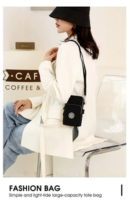 Detail of a black nylon crossbody phone bag shown in a cozy cafe setting for women