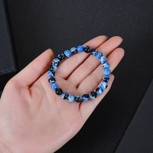 Blauw en zwart agaat kralenarmband in de hand gehouden op donkere achtergrond