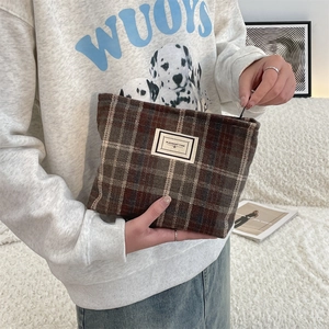 Close-up of a plaid wool cosmetic bag held by hands with Pleasant Time label