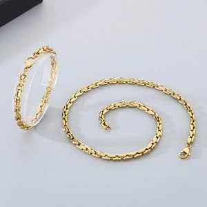 Detailansicht einer goldenen Edelstahl-Gliederkette und eines Armbands auf Ständer