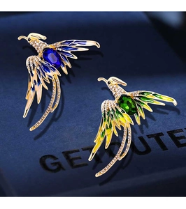 Macro detail of phoenix brooch featuring sparkling rhinestones and blue emerald-cut gem