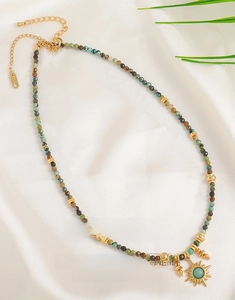 Detail of colorful natural stone beaded necklace with a golden sun pendant on silk