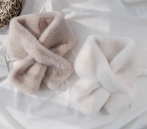 Dettaglio di sciarpe in ecopelliccia peluche beige e bianca con design incrociato