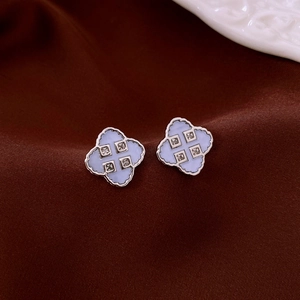 Macro shot of silver four-leaf clover earrings with lavender enamel and diamond accents