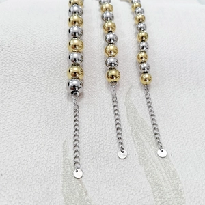 Detail view of two-tone gold and silver beaded bracelets with S925 stamped extension chains