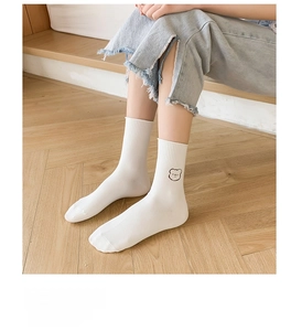 Close-up of white ribbed cotton socks featuring a minimalist cartoon bear embroidery