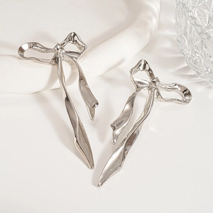 Gros plan de boucles d'oreilles nœud argentées avec texture métal liquide fluide