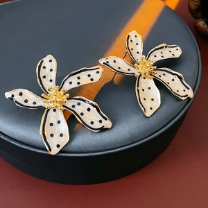 Close-up of vintage flower earrings with black and white polka dots and gold stamens