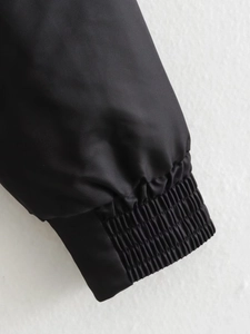 Detailed view of elastic ribbed cuffs on a black flight jacket with smooth fabric