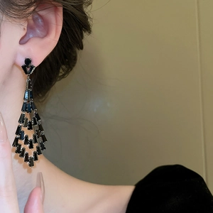 Detail view of long tassel earrings with black geometric crystals and dangling rhinestones