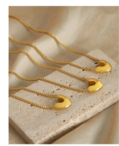 Vue détaillée de trois colliers à pendentif cœur plaqué or sur un présentoir en pierre