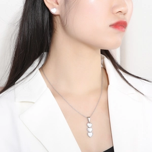 Detail of silver heart-shaped necklace and earrings set with white shell inlay